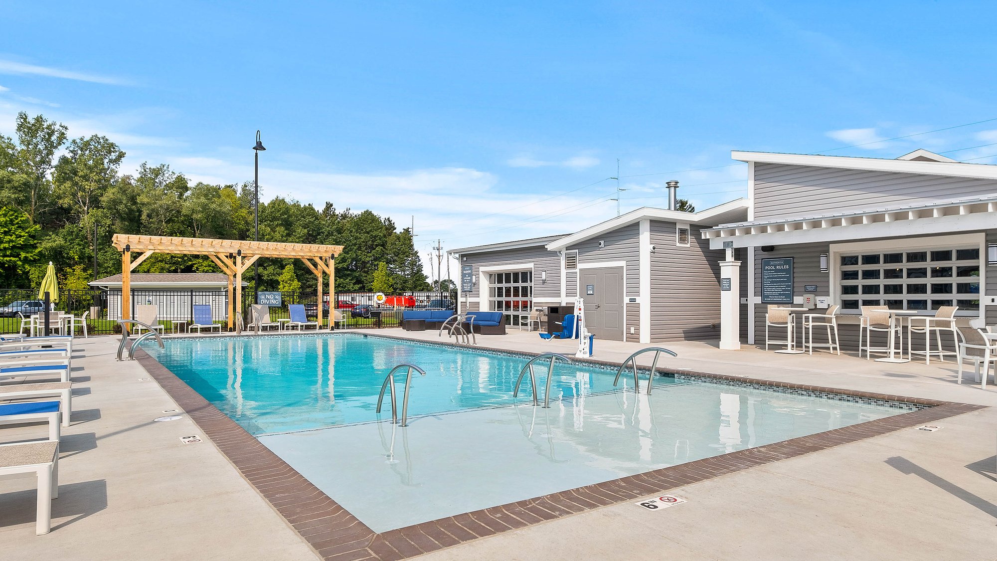Outdoor pool with lounge chairs, and modern clubhouse seating at Authentix Town Creek in Lenoir City, TN.