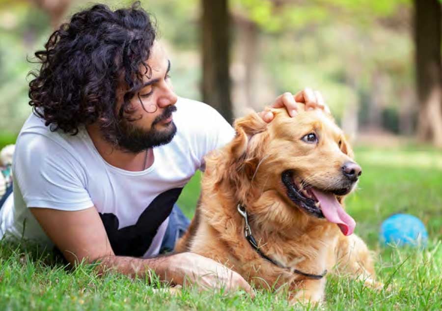 man_laying_with_dog_in_park