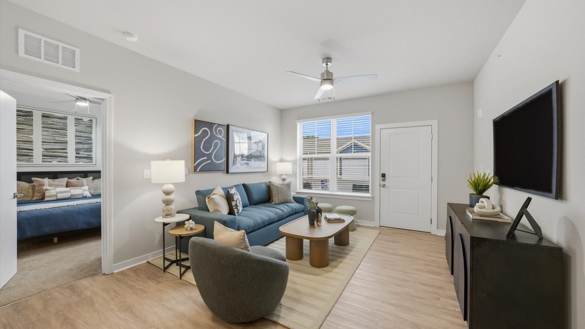 Open living layout in 2 bedroom model with contemporary furnishings and natural light, steps from the front entry at Authentix Town Creek.
