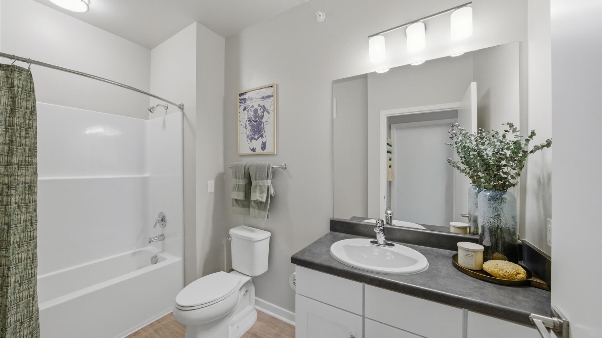 Bathroom with white tub/shower, green curtain, and matching towel set at Authentix Town Creek in Lenoir City, TN.