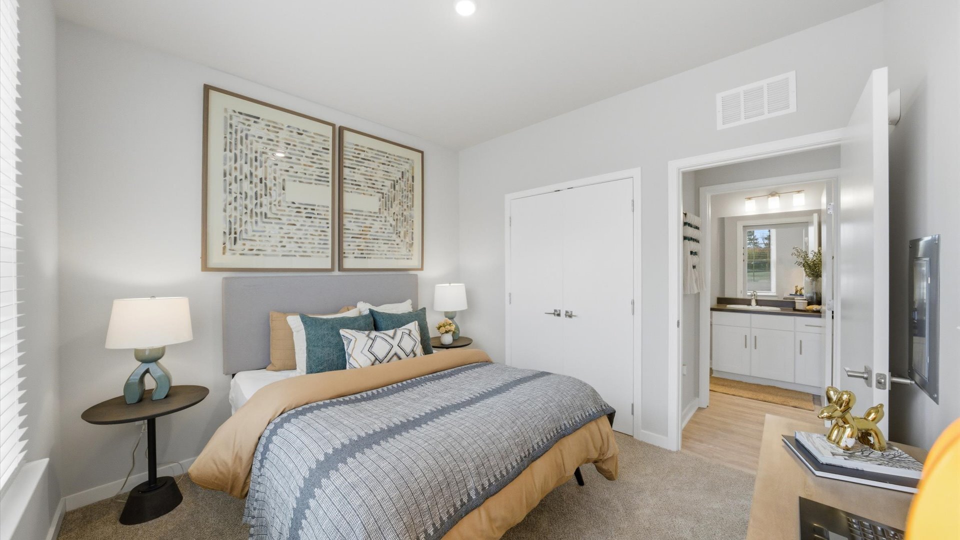 Bedroom with gray and gold bedding, double closet doors, and ensuite bath access at Authentix Town Creek Apartments Near Knoxville, TN.