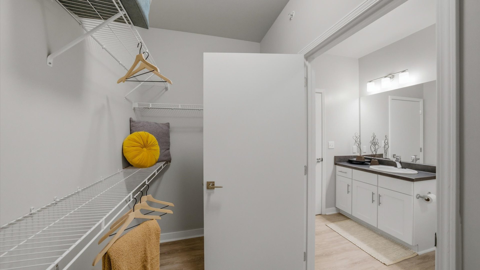 Walk‑in closet with wire shelving leading to single‑vanity bath at Authentix Town Creek Apartments in Lenoir City, TN.