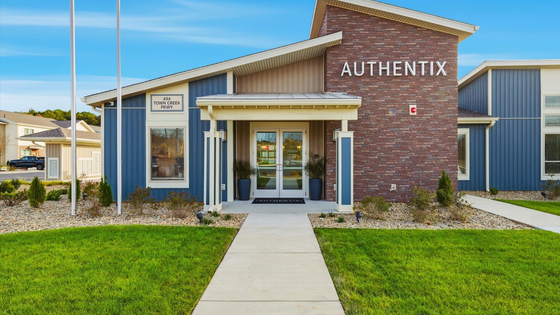 Modern community building with tall windows and flagpoles at Authentix Town Creek.