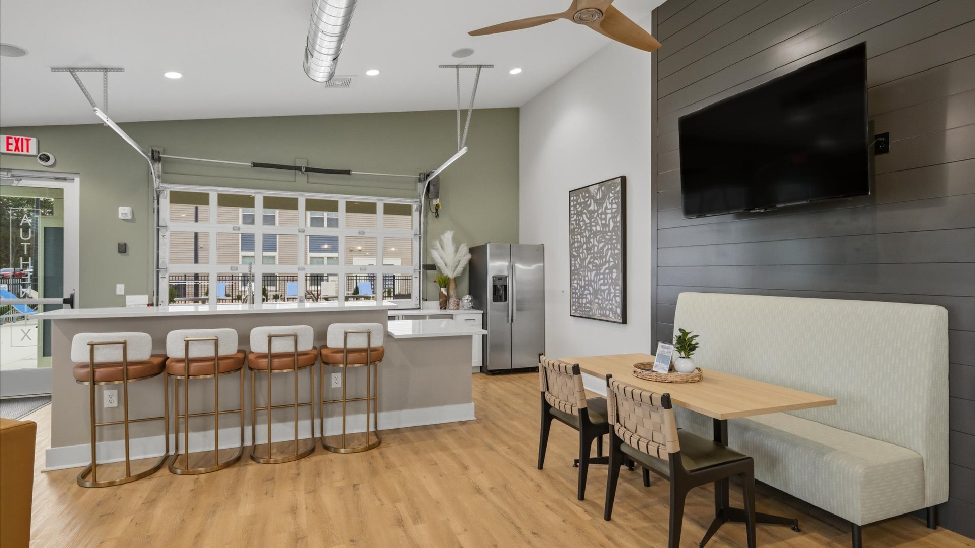 Clubhouse bar with four stools, banquette seating, and wall‑mounted TV at Authentix Town Creek Apartments in Lenoir City, TN.