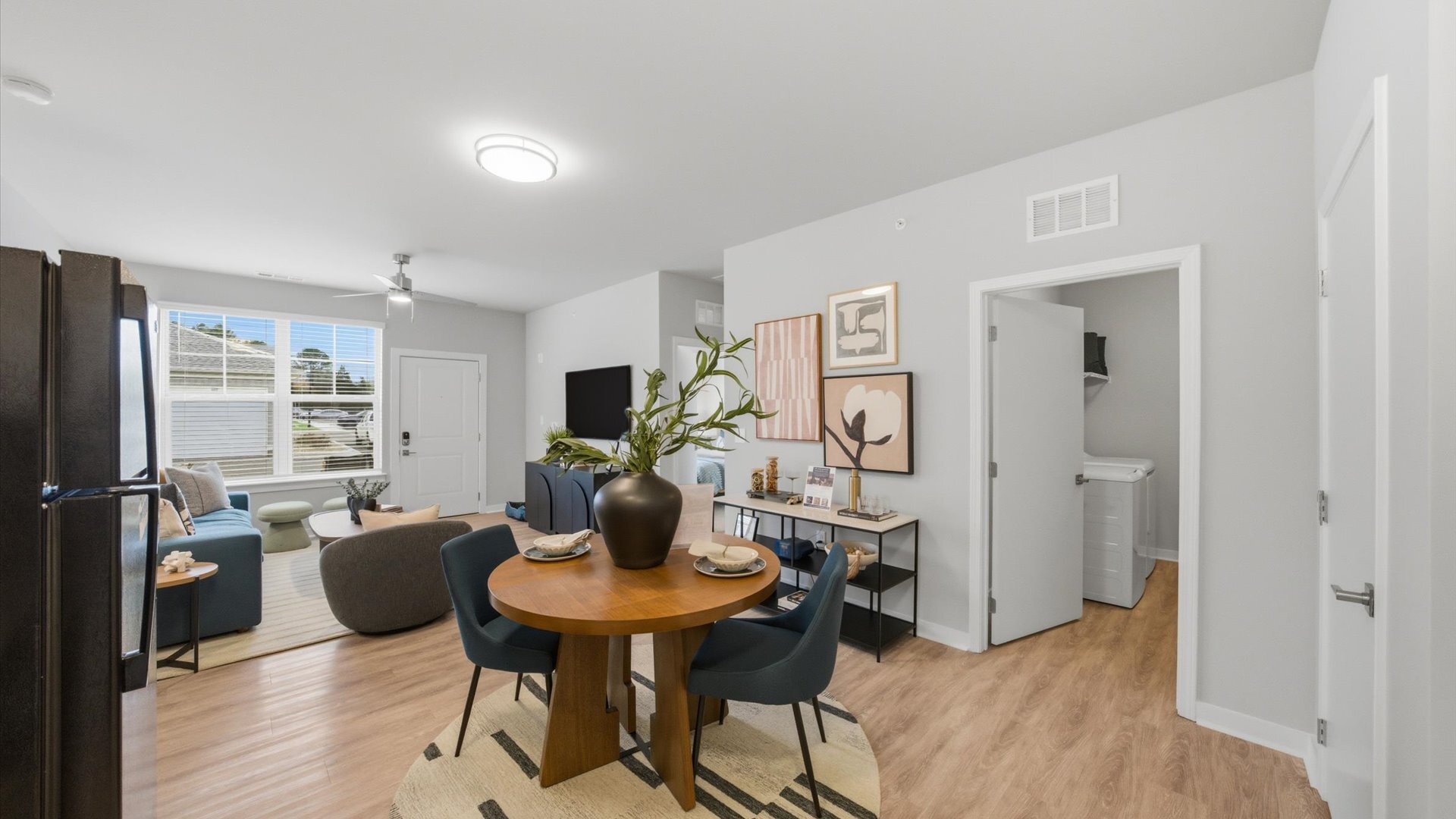 Dining nook with round table and blue chairs opening to living room and kitchen at Authentix Town Creek, Lenoir City, TN.