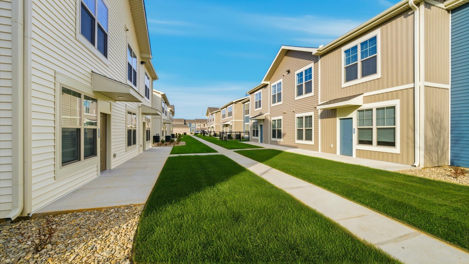 Apartments with direct entry and private yards available with tan and blue siding, and sidewalks in Lenoir City, TN.