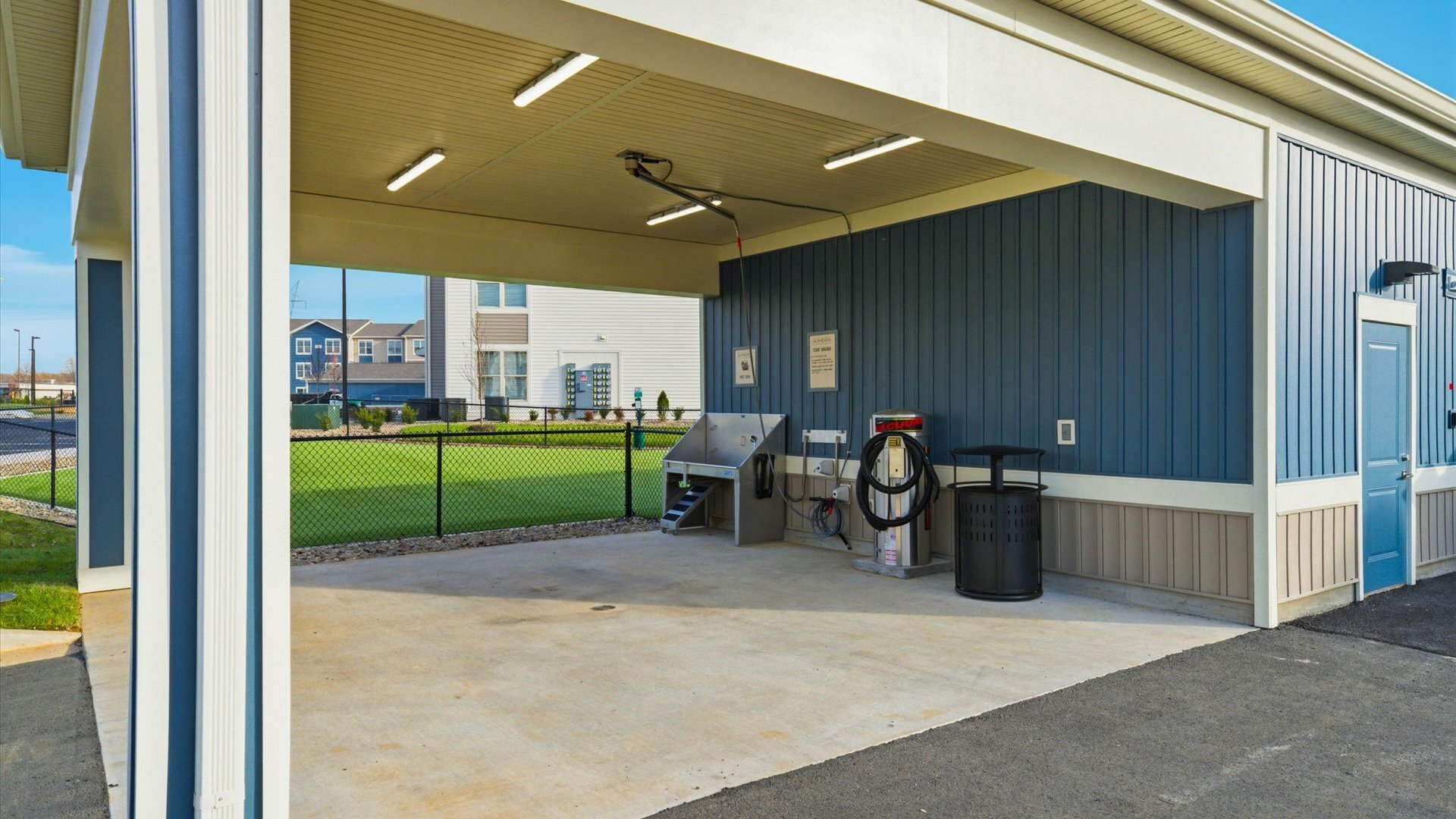 Community pet spa and car wash with elevated bath, hose sprayer, and car vacuum amenities.
